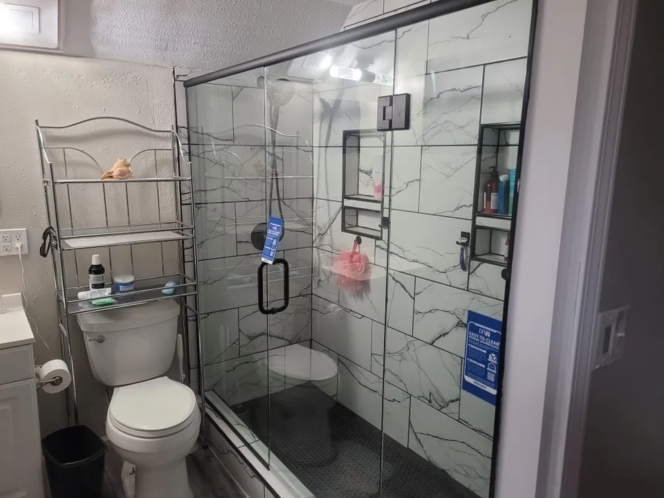 The finished basement shower with frameless glass doors and black hardware