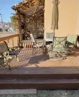 The same backyard after: an elevated wood deck with seating under a pergola